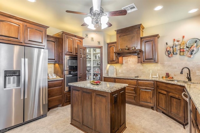 kitchen featuring visible vents, a center island, stainless steel appliances, premium range hood, and a sink