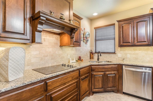 kitchen featuring light stone counters, stainless steel dishwasher, a sink, and black electric cooktop