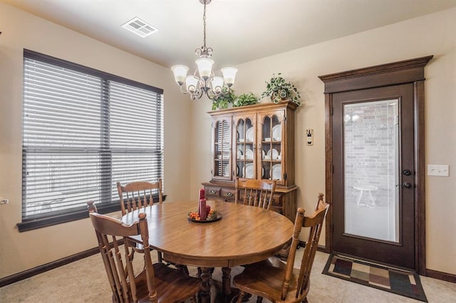 dining space featuring visible vents, a notable chandelier, and baseboards