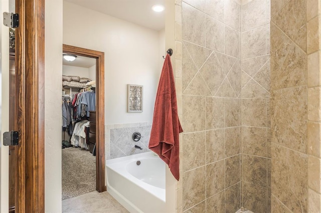 bathroom featuring a spacious closet, a garden tub, and tile patterned floors