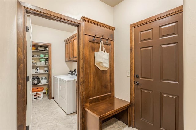 clothes washing area featuring separate washer and dryer and cabinet space