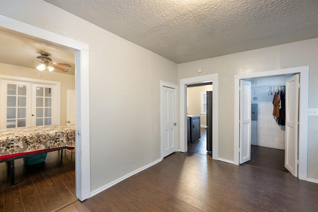 interior space with baseboards, a textured wall, dark wood-style floors, a textured ceiling, and french doors