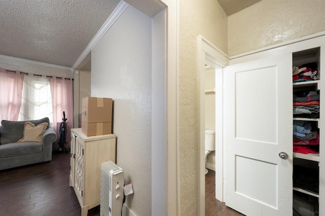 hallway featuring dark wood-style floors, ornamental molding, a textured ceiling, and a textured wall