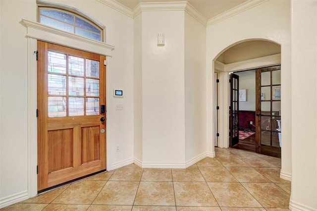 foyer featuring arched walkways, crown molding, baseboards, and light tile patterned floors