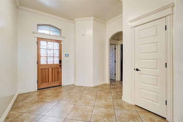 entryway featuring arched walkways, light tile patterned floors, baseboards, and crown molding