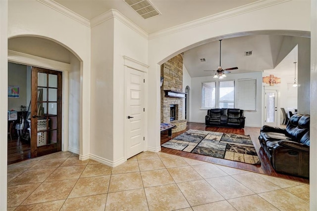 living area featuring ornamental molding, visible vents, a fireplace, and light tile patterned flooring