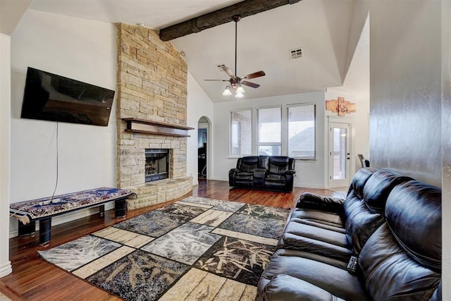 living area with visible vents, wood finished floors, beamed ceiling, a stone fireplace, and high vaulted ceiling