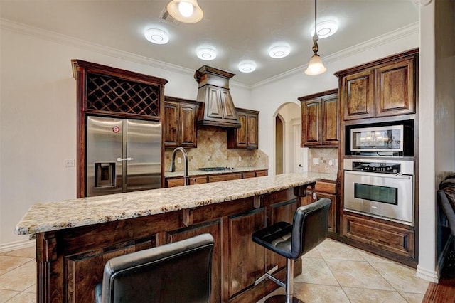 kitchen with light tile patterned floors, arched walkways, stainless steel appliances, crown molding, and a sink