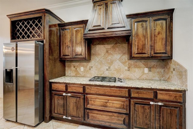 kitchen featuring custom range hood, appliances with stainless steel finishes, decorative backsplash, and light stone counters