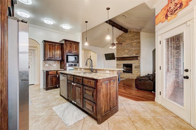 kitchen featuring arched walkways, stainless steel appliances, backsplash, light tile patterned flooring, and a sink