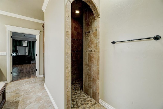 bathroom with tile patterned flooring, crown molding, baseboards, and tiled shower