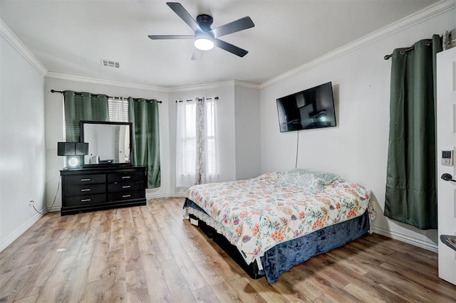 bedroom with baseboards, wood finished floors, visible vents, and crown molding