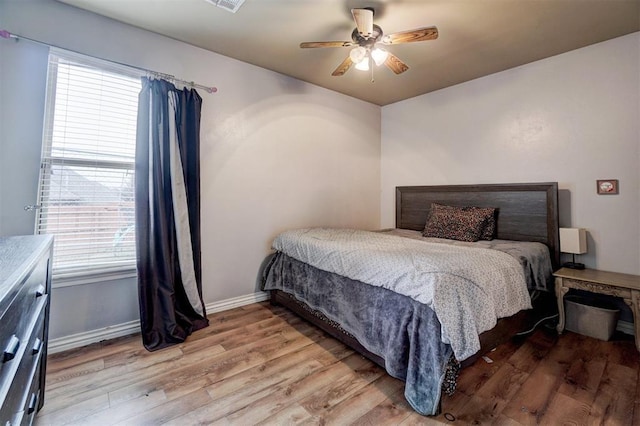 bedroom with light wood-style flooring, visible vents, baseboards, and a ceiling fan