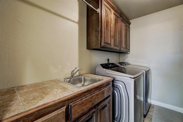 clothes washing area featuring cabinet space, baseboards, washer and clothes dryer, and a sink