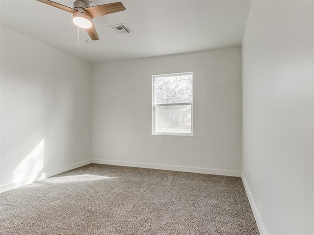 carpeted empty room featuring ceiling fan, visible vents, and baseboards