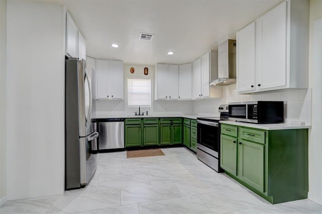 kitchen featuring visible vents, stainless steel appliances, wall chimney range hood, green cabinets, and a sink