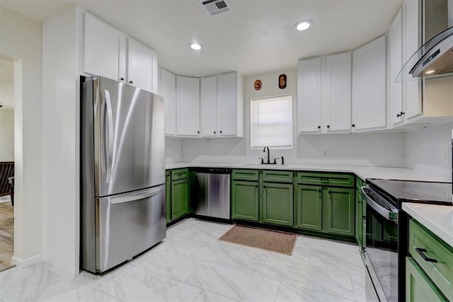 kitchen with white cabinets, stainless steel appliances, wall chimney range hood, green cabinets, and a sink