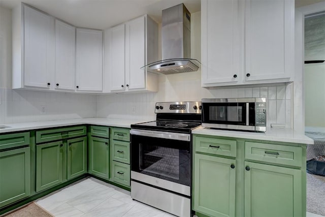 kitchen featuring light countertops, appliances with stainless steel finishes, white cabinets, green cabinetry, and wall chimney exhaust hood