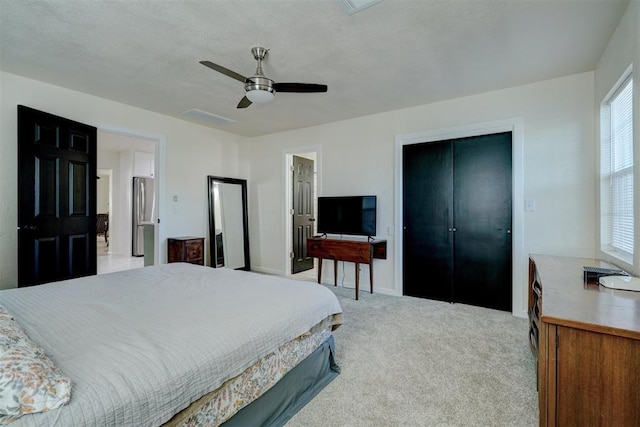 bedroom featuring ceiling fan, light colored carpet, baseboards, a closet, and freestanding refrigerator