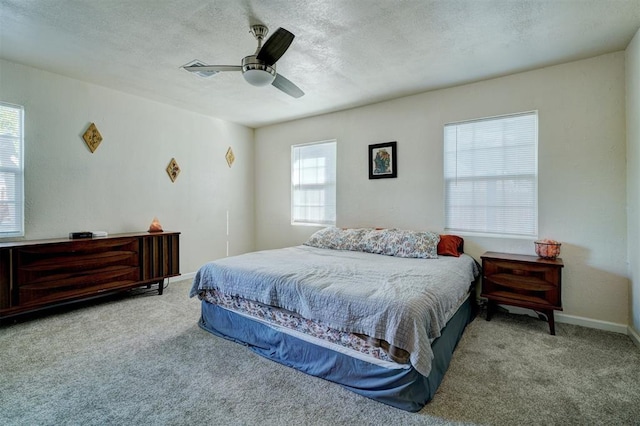 carpeted bedroom featuring ceiling fan, baseboards, and a textured ceiling