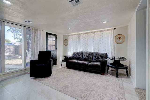 living area featuring recessed lighting, visible vents, and a textured ceiling