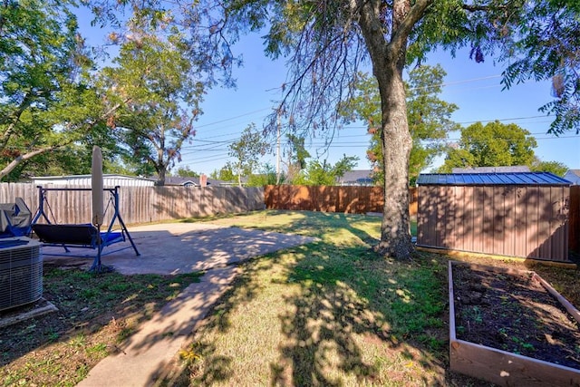 view of yard with a vegetable garden, a patio, a fenced backyard, an outbuilding, and a storage unit