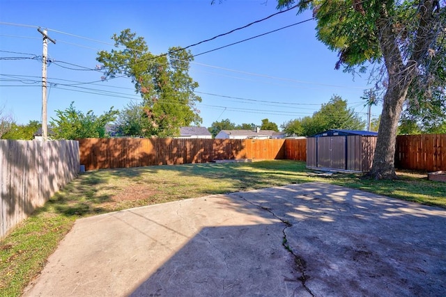 view of yard with a patio area, an outdoor structure, a fenced backyard, and a storage shed