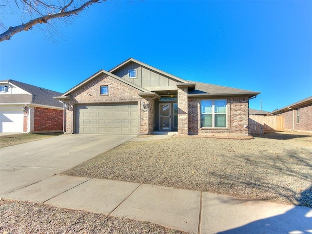 view of front of property with brick siding, an attached garage, driveway, and fence