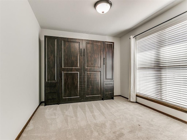 unfurnished bedroom with light carpet and baseboards