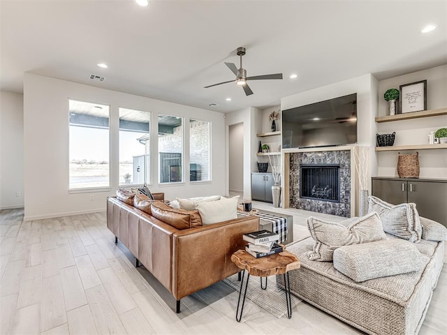 living area featuring light wood finished floors, a tile fireplace, visible vents, and recessed lighting