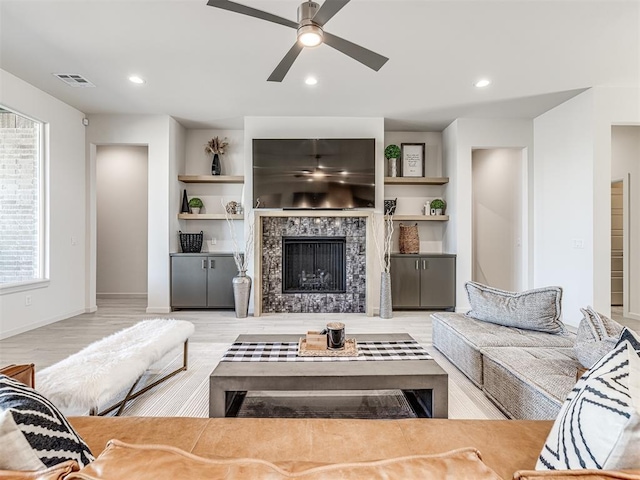 living area featuring built in shelves, a tile fireplace, recessed lighting, visible vents, and baseboards