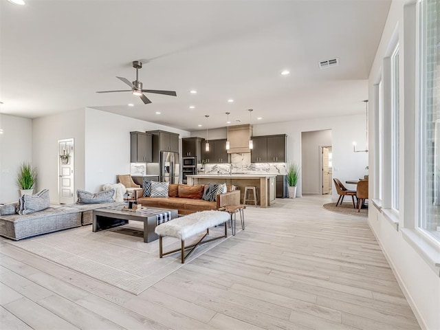 living room with ceiling fan, recessed lighting, visible vents, baseboards, and light wood-style floors