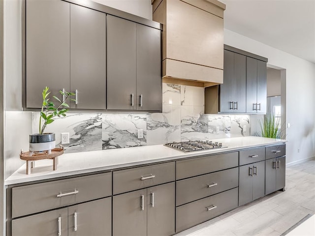 kitchen with light countertops, stainless steel gas cooktop, backsplash, and gray cabinetry