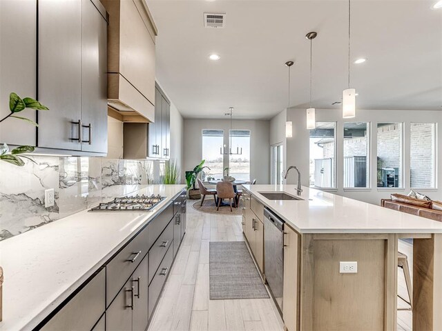 kitchen featuring stainless steel appliances, a sink, visible vents, light countertops, and tasteful backsplash