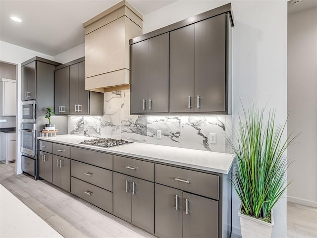 kitchen with stainless steel appliances, gray cabinets, light countertops, and backsplash