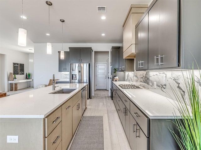 kitchen featuring stainless steel appliances, light countertops, visible vents, decorative backsplash, and a sink