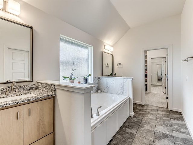 bathroom featuring a garden tub, baseboards, vaulted ceiling, and vanity