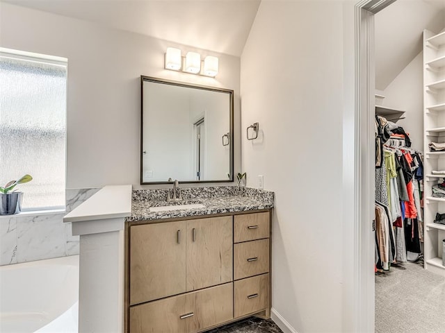 full bath featuring a garden tub, baseboards, a walk in closet, and vanity