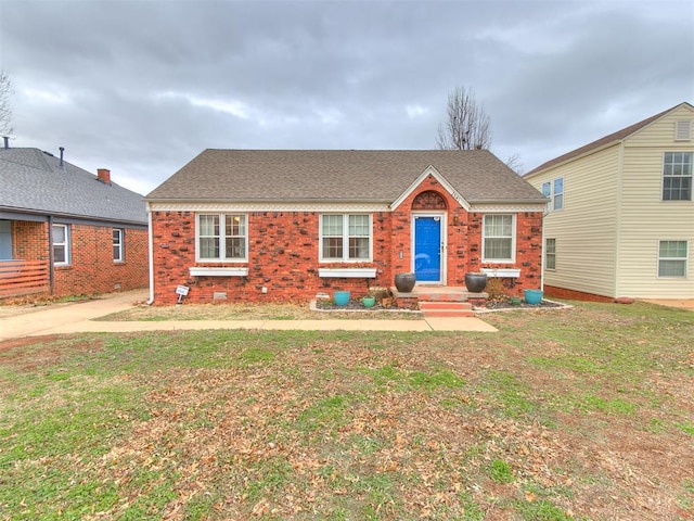 view of front of house with roof with shingles, brick siding, and a front lawn