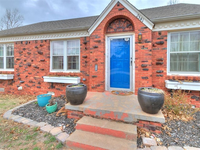 doorway to property featuring crawl space, a shingled roof, and brick siding