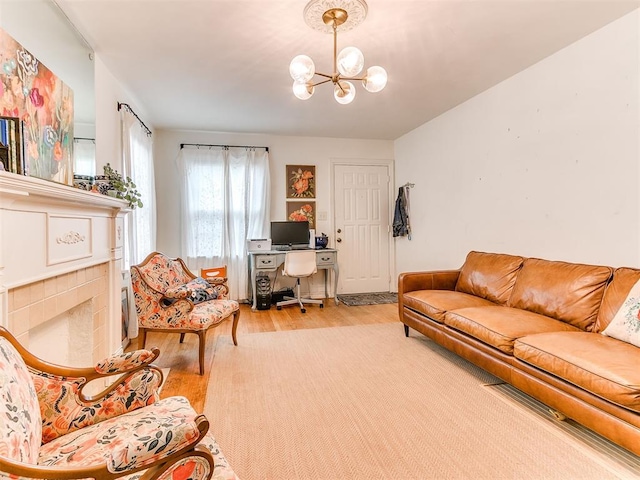 living room featuring a chandelier, a tiled fireplace, and wood finished floors