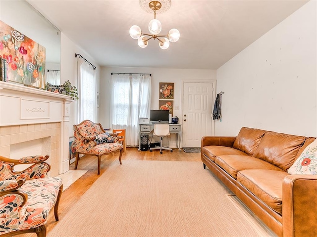 living area featuring light wood-type flooring, a tile fireplace, and an inviting chandelier