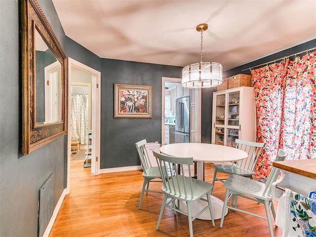 dining space featuring light wood finished floors, visible vents, and baseboards