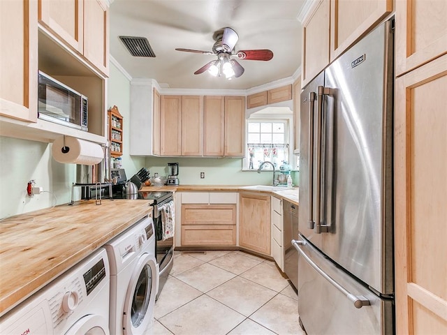 kitchen with separate washer and dryer, visible vents, appliances with stainless steel finishes, light brown cabinetry, and crown molding