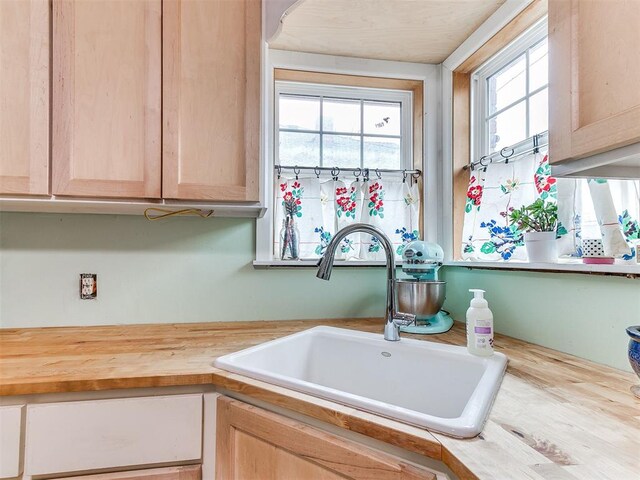 kitchen featuring a healthy amount of sunlight, butcher block countertops, a sink, and light brown cabinetry