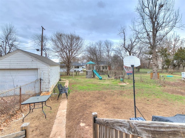 view of yard with an outbuilding, a playground, fence, and a garage