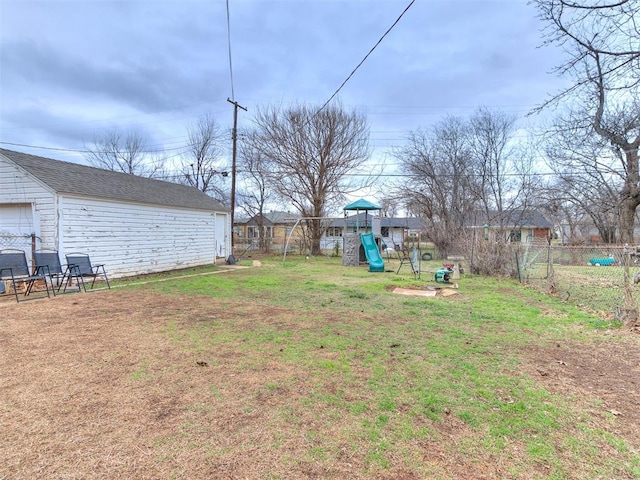 view of yard with fence, a playground, and an outdoor structure