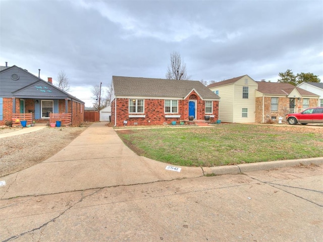 view of front of house featuring an outdoor structure, roof with shingles, a front lawn, and brick siding