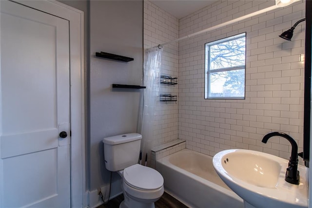 bathroom with toilet, tub / shower combination, and a sink