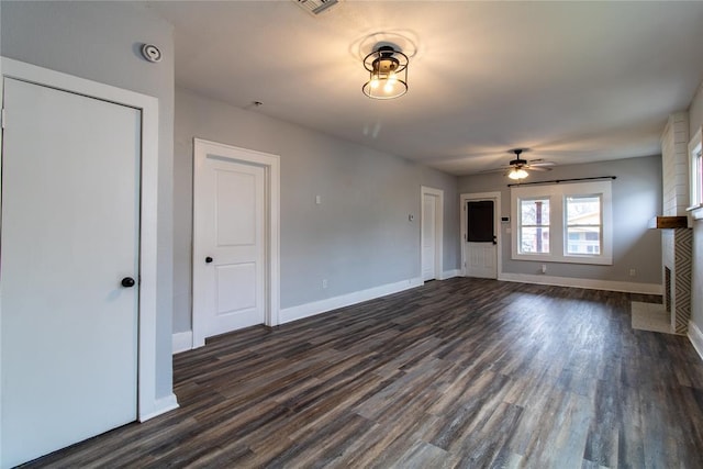 unfurnished living room with a fireplace with flush hearth, dark wood-type flooring, baseboards, and a ceiling fan